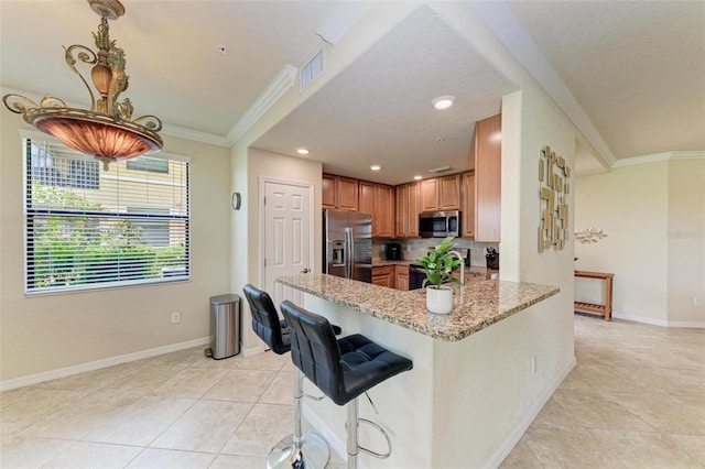 kitchen with ornamental molding, light stone counters, kitchen peninsula, appliances with stainless steel finishes, and light tile patterned flooring