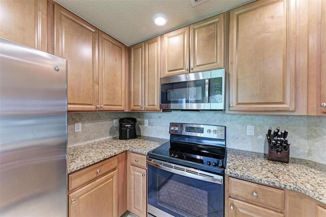 kitchen featuring appliances with stainless steel finishes, tasteful backsplash, and light stone countertops