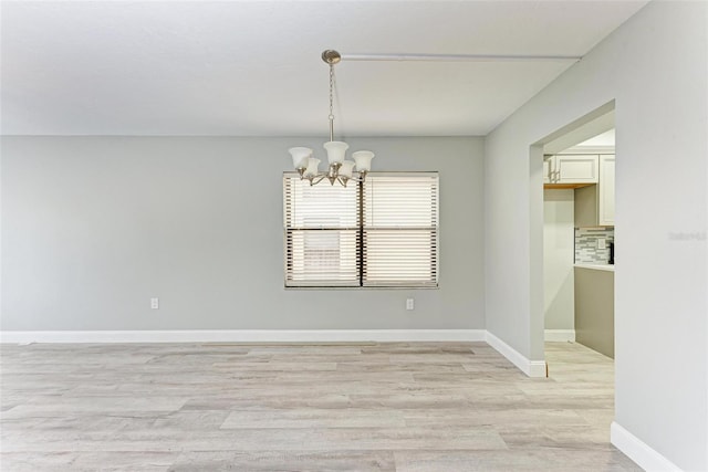 unfurnished dining area featuring light wood-type flooring and a chandelier