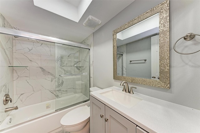 full bathroom featuring vanity, toilet, bath / shower combo with glass door, and a skylight