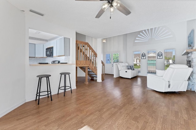 living room with visible vents, ceiling fan, wood finished floors, stairs, and a fireplace