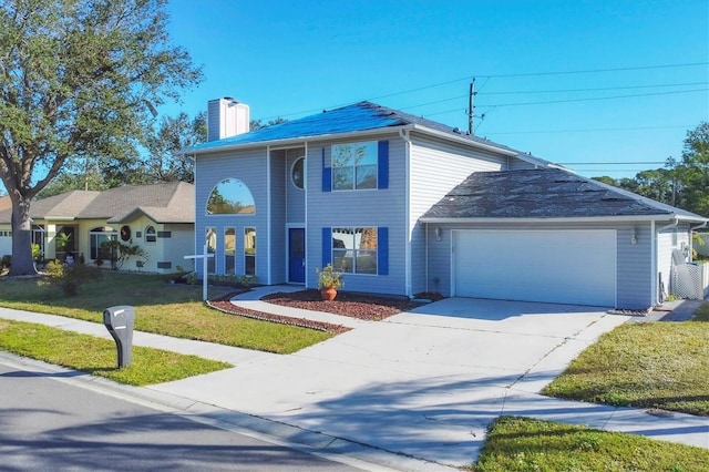 traditional-style home with a garage, concrete driveway, a chimney, and a front yard