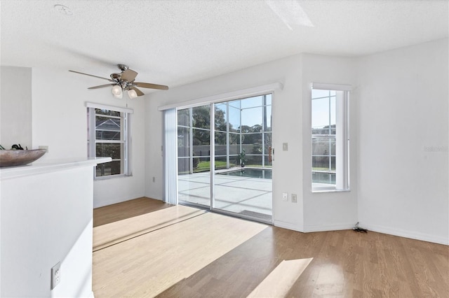 entryway with a textured ceiling, wood finished floors, a ceiling fan, and baseboards