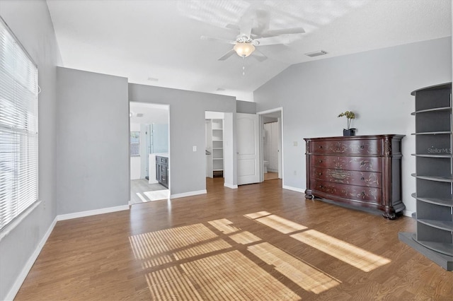 unfurnished bedroom with lofted ceiling, a spacious closet, visible vents, and wood finished floors