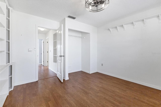 spare room featuring a textured ceiling, wood finished floors, visible vents, and baseboards