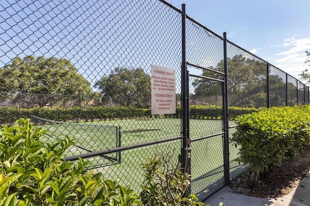 view of tennis court featuring a gate and fence