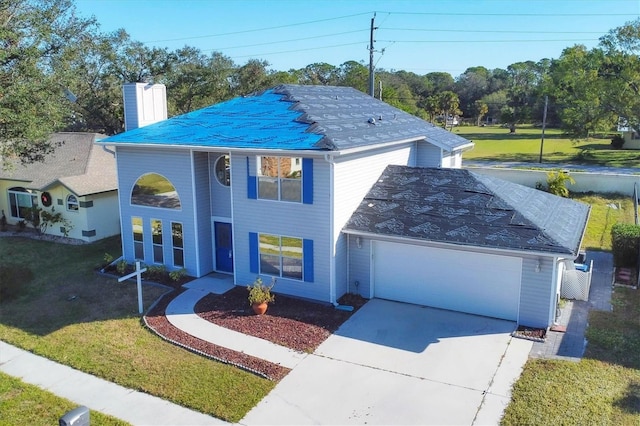 view of front of house featuring concrete driveway, a front lawn, a chimney, and an attached garage