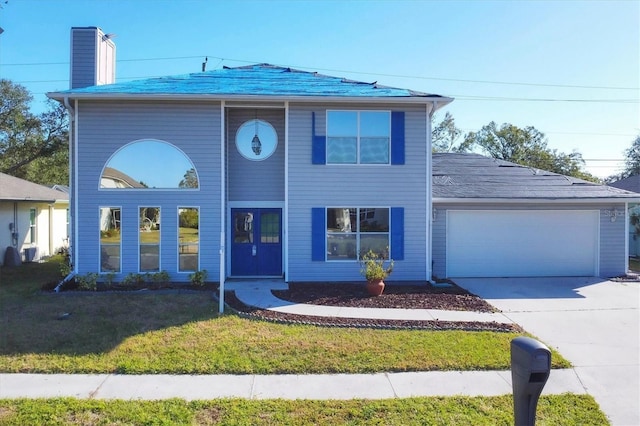 view of front facade featuring driveway, a chimney, an attached garage, and a front yard