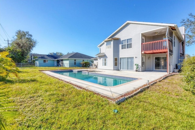 rear view of house with ceiling fan, fence, a yard, a fenced in pool, and a patio area