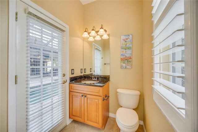 half bathroom featuring tile patterned flooring, baseboards, toilet, plenty of natural light, and vanity