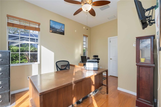 office area with light wood finished floors, visible vents, a ceiling fan, and baseboards