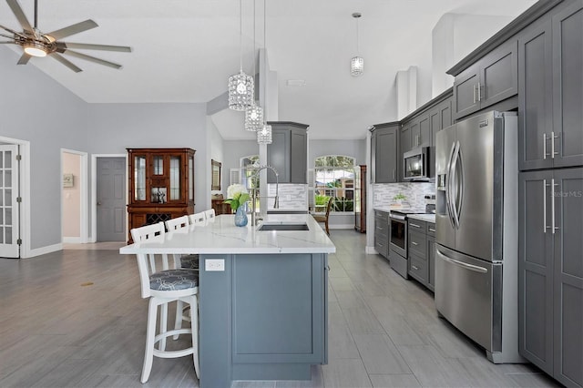 kitchen featuring decorative light fixtures, gray cabinets, sink, and stainless steel appliances