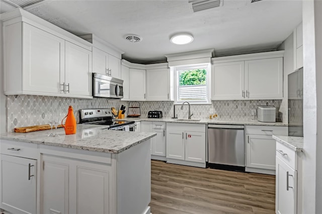 kitchen featuring appliances with stainless steel finishes, light stone counters, kitchen peninsula, and white cabinets