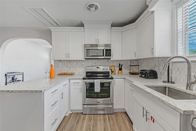 kitchen with light wood-type flooring, white cabinets, stainless steel appliances, and sink