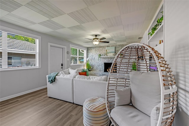 living room featuring ceiling fan, a fireplace, and wood-type flooring