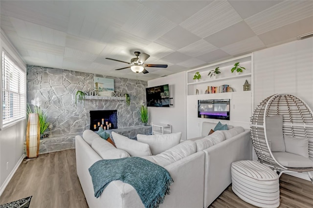 living room featuring ceiling fan, a fireplace, and wood-type flooring