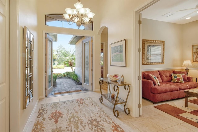 tiled entrance foyer featuring arched walkways and ceiling fan with notable chandelier