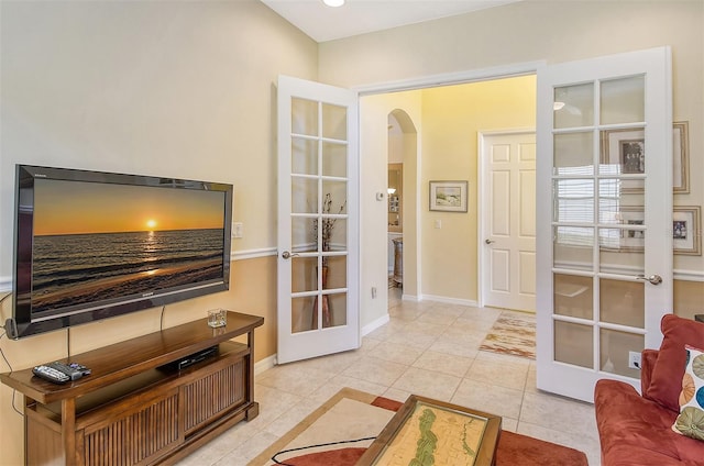 living room with arched walkways, french doors, light tile patterned floors, and baseboards