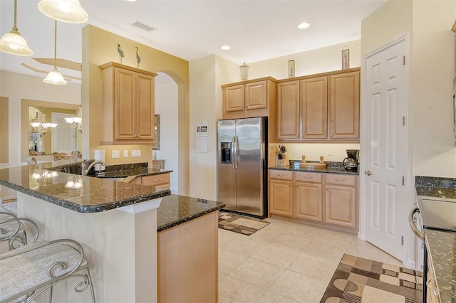 kitchen featuring light tile patterned floors, a sink, a kitchen breakfast bar, stainless steel fridge with ice dispenser, and dark stone counters