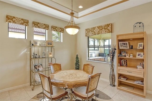 dining area with light tile patterned floors, baseboards, and a tray ceiling