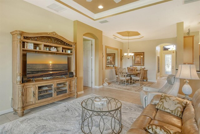 living area featuring a tray ceiling, arched walkways, a notable chandelier, and light tile patterned flooring