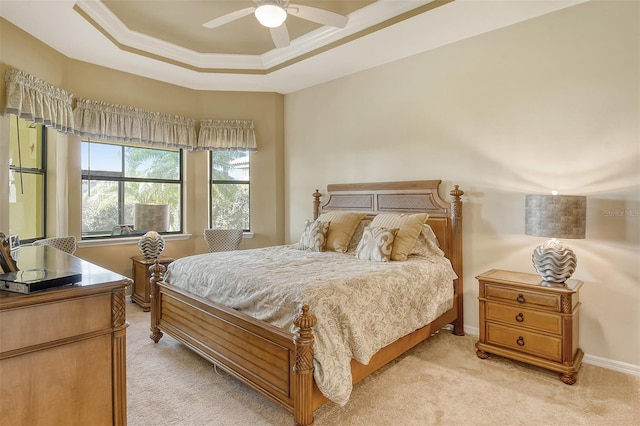 bedroom featuring light carpet, a ceiling fan, baseboards, a raised ceiling, and crown molding