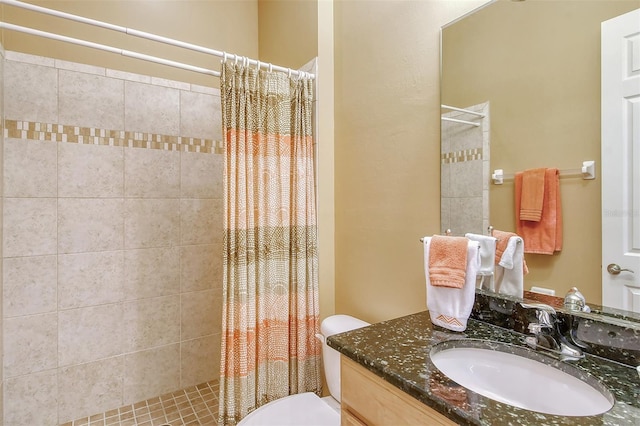 bathroom featuring toilet, tiled shower, and vanity