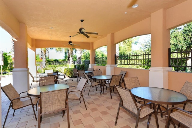 view of patio featuring ceiling fan, outdoor dining space, and fence