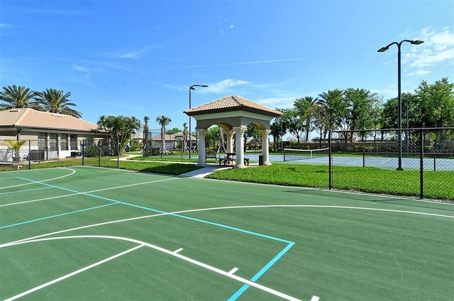 view of sport court with a tennis court, fence, and a gazebo