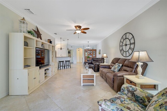 tiled living room with ceiling fan with notable chandelier and crown molding