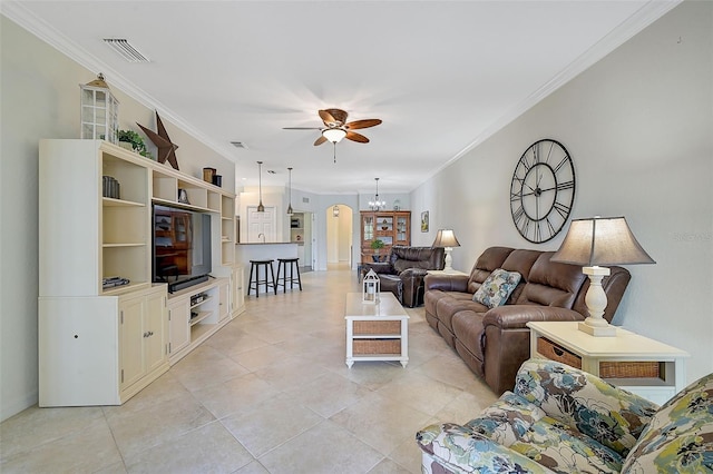 living room featuring crown molding, light tile patterned floors, ceiling fan with notable chandelier, and visible vents