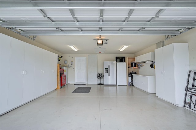 garage with white fridge, white refrigerator with ice dispenser, and a garage door opener