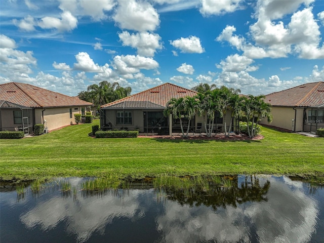 rear view of house with a water view, a lanai, and a lawn