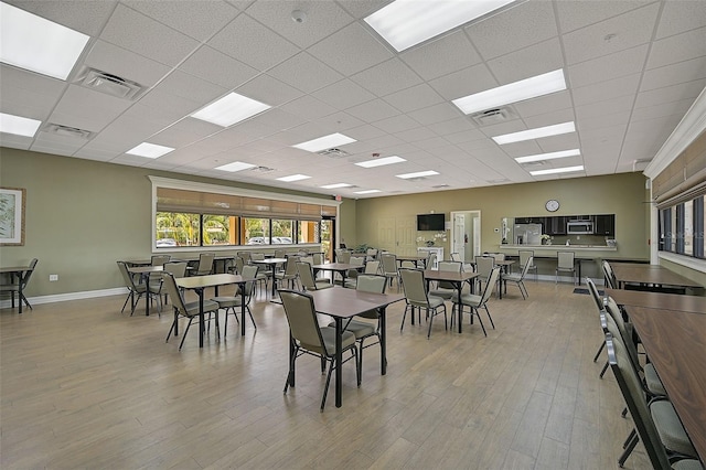 dining space featuring a drop ceiling and light hardwood / wood-style flooring