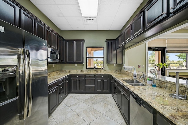 kitchen featuring light stone countertops, plenty of natural light, stainless steel appliances, and sink