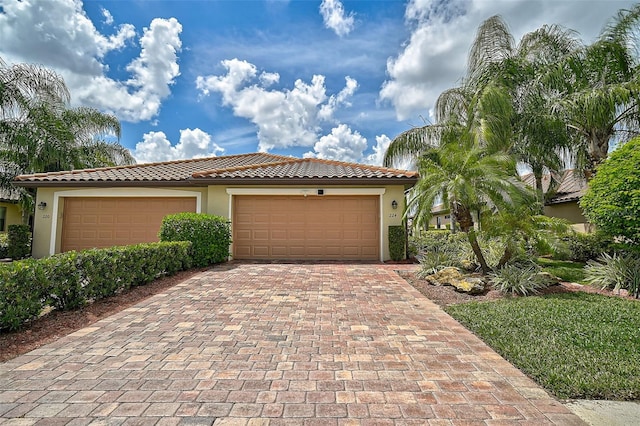 view of front of home featuring a tile roof, decorative driveway, a garage, and stucco siding