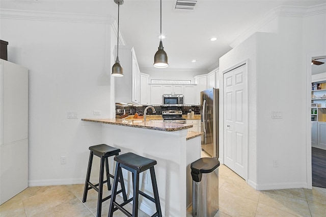 kitchen featuring stainless steel appliances, backsplash, kitchen peninsula, stone countertops, and decorative light fixtures