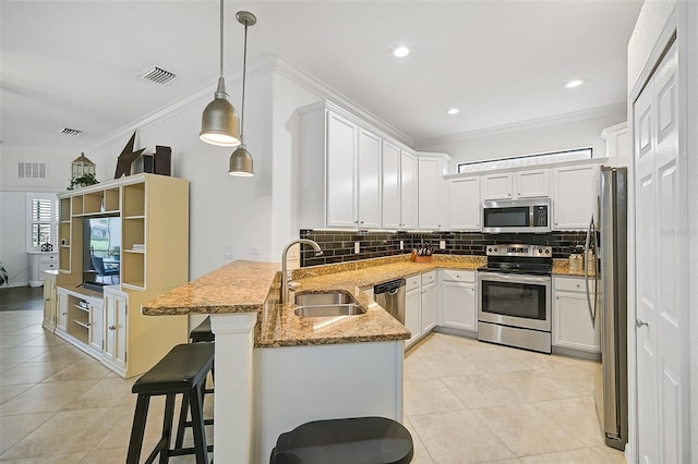 kitchen featuring pendant lighting, white cabinets, sink, appliances with stainless steel finishes, and kitchen peninsula