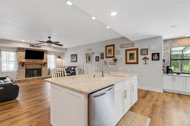 kitchen featuring plenty of natural light, dishwasher, a fireplace, and a center island with sink