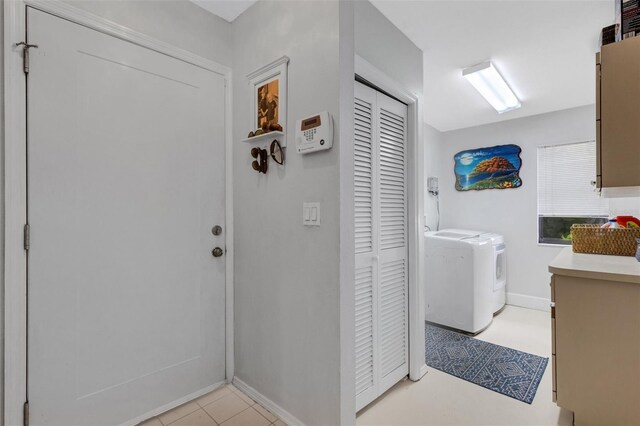 laundry area with washer and clothes dryer and light tile patterned floors