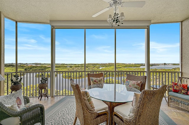 sunroom featuring a healthy amount of sunlight, a water view, and ceiling fan