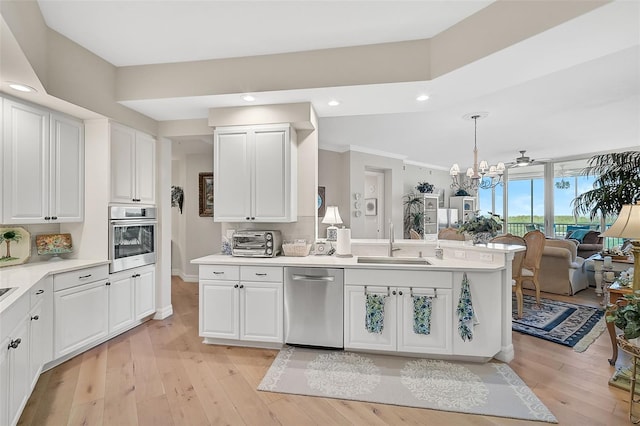 kitchen with pendant lighting, white cabinets, appliances with stainless steel finishes, and sink