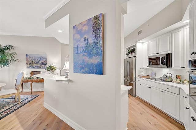 kitchen featuring decorative backsplash, white cabinetry, light hardwood / wood-style flooring, and stainless steel appliances