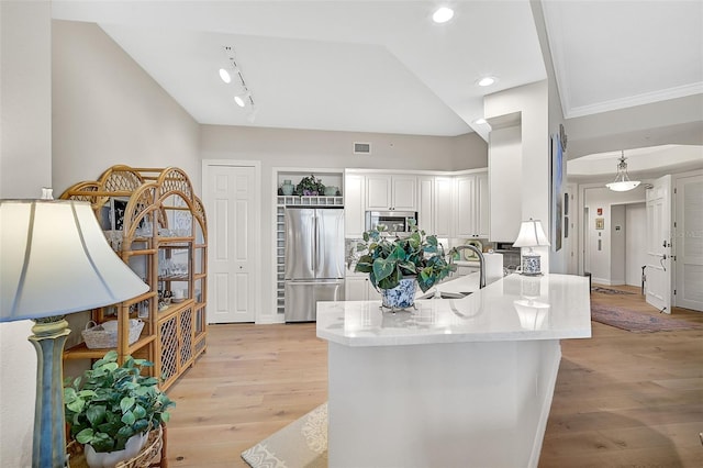 kitchen with white cabinets, stainless steel appliances, light wood-type flooring, lofted ceiling, and sink