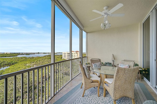 sunroom with a water view and ceiling fan