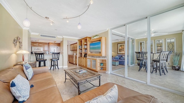 living area with light tile patterned floors, baseboards, visible vents, a ceiling fan, and crown molding