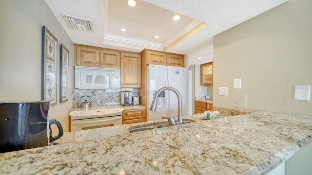 kitchen featuring a tray ceiling, visible vents, a sink, light stone countertops, and white appliances