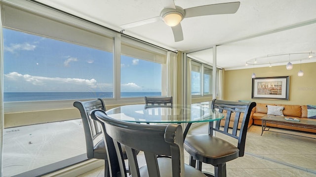 sunroom / solarium featuring ceiling fan and a water view