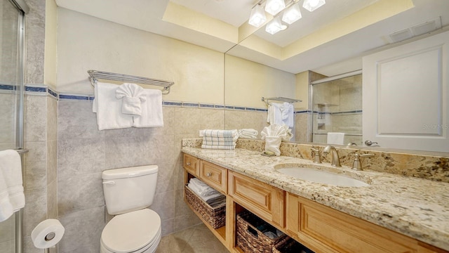 bathroom with toilet, vanity, visible vents, tile walls, and tiled shower