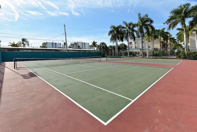 view of tennis court with community basketball court and fence